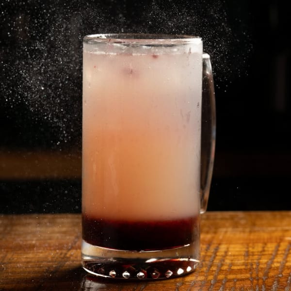 A Plant City Comic Cafe drink with dark liquid at the bottom and lighter liquid on top.